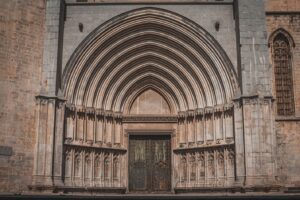 Ornate stone cathedral entrance: arched portal, carved columns, dark double doors